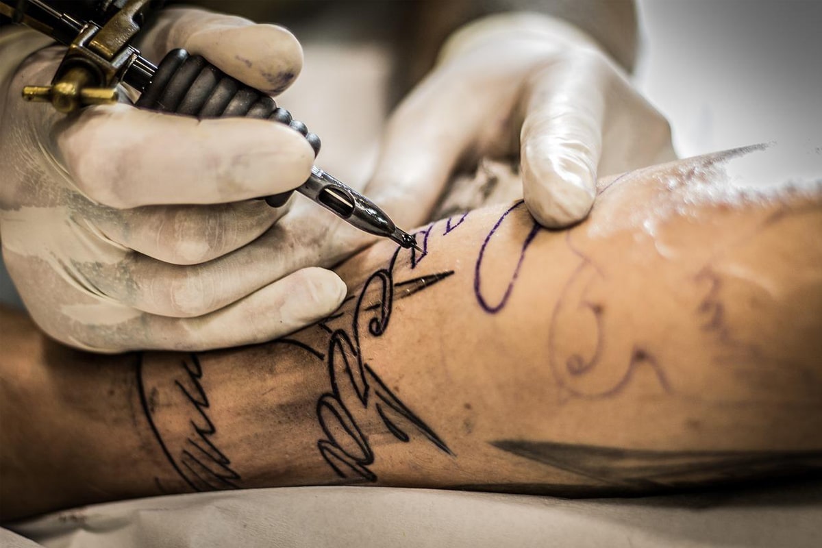 tatuador com cuidados essenciais para fazer uma tatuagem