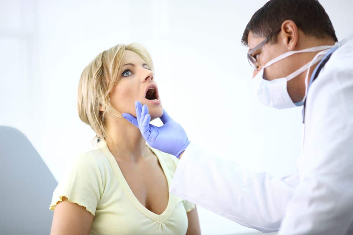 médico avaliando afta na boca