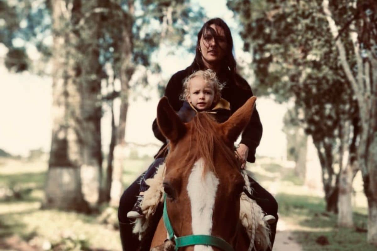Heloísa Santos com seu filho Oliver montados em um cavalo.